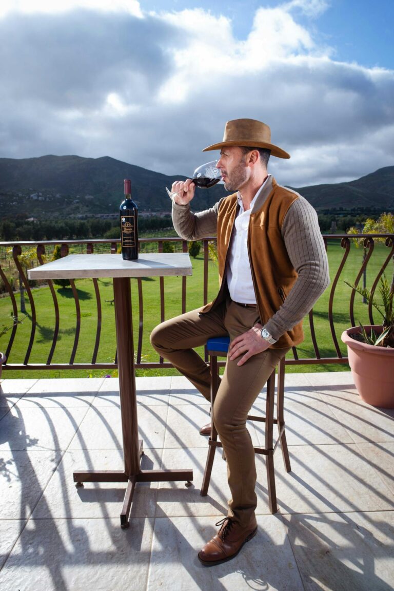 Man savoring wine on a sunny terrace with vineyard views in Valle de Guadalupe, Mexico.
